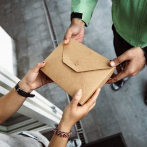 A delivery person hands over a package to a customer outdoors, showing modern service interaction.